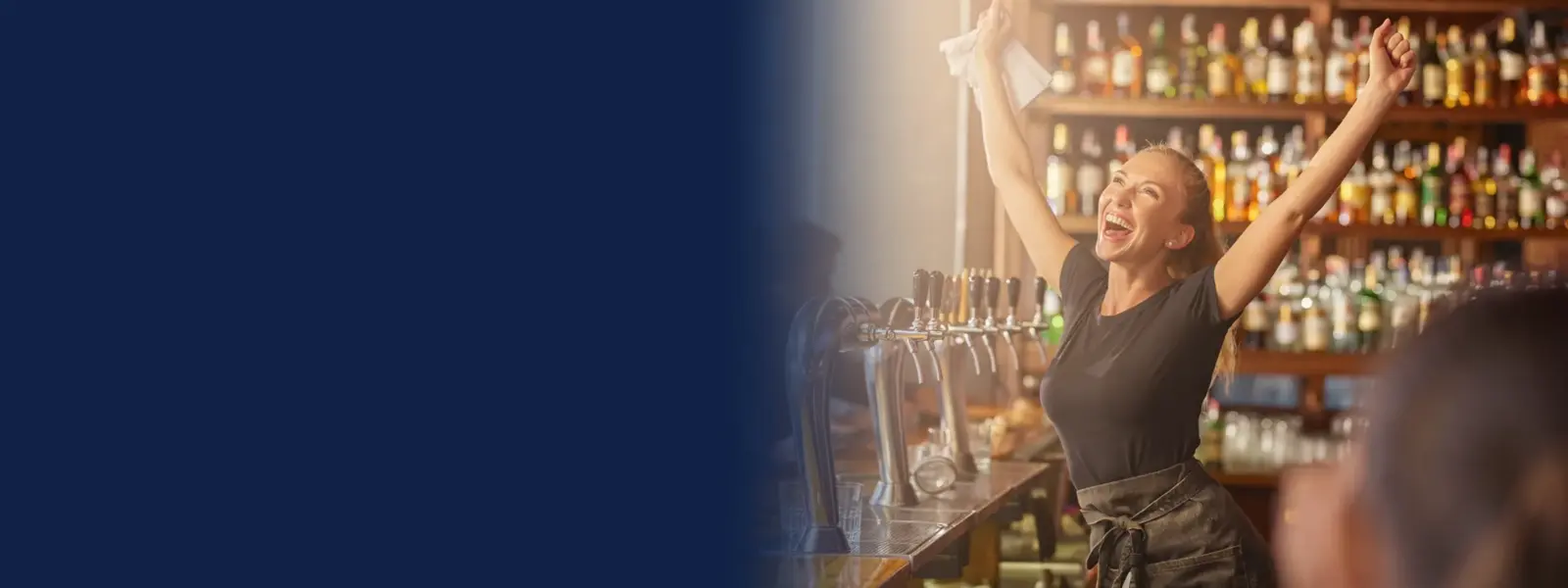 Bartender celebrating behind a busy pub bar